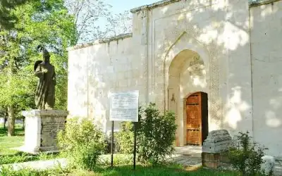 Atabey Ertokuş Kümbeti yeşil bahçe alanında yapı silüeti